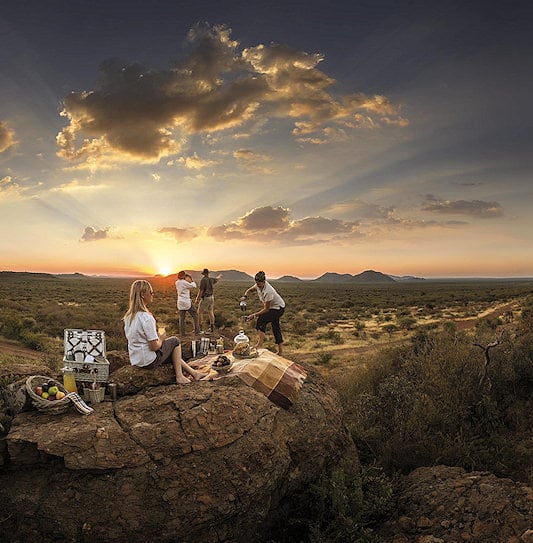 Tourists in South Africa enjoying a scenic bush picnic while on safari at Madikwe Game Reserve.