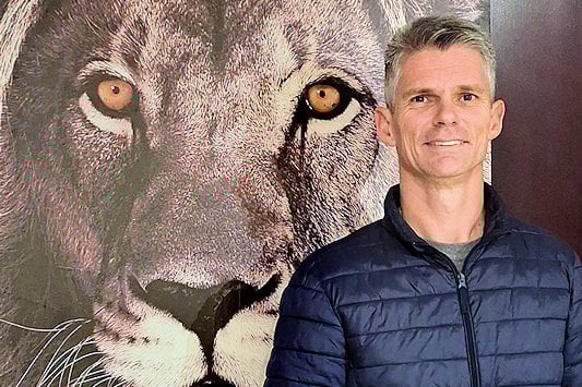 Leon van Staden standing in front of a large lion painting.