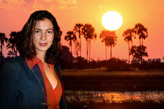 Mary-Anne Finlay with a fiery sunset over the Okavango Delta in the background.