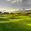 A green golf course fairway with mountains in the background.