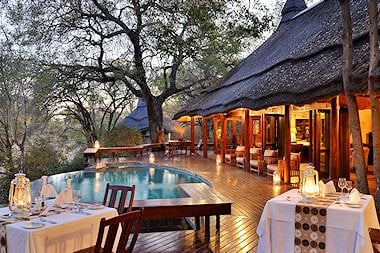 A latern-lit dinner set up around the pool deck at Imbali Safari Lodge.