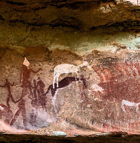 San rock art paintings depicting human figures and animals on a rock face.