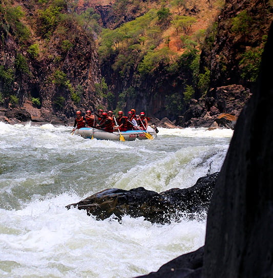 People white-water rafting through a rocky river gorge, Zambia.