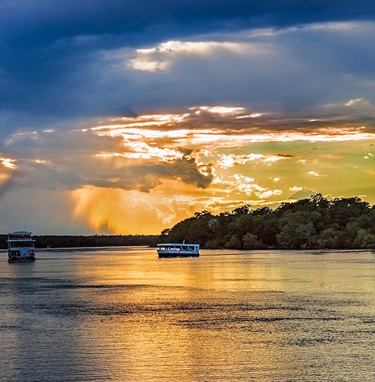 Cruise boats on the Zambezi River at sunset.