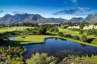 A golf course with a water hazard in front of mountains on the Garden Route.