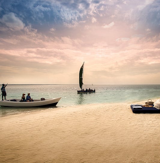 Guests on vacation in Mozambique arriving by boat at a private sandbank for a luxury beach picnic.