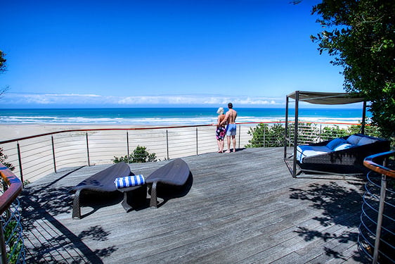 Couple standing on a timber viewing platform looking out across an Eastern Cape beach.