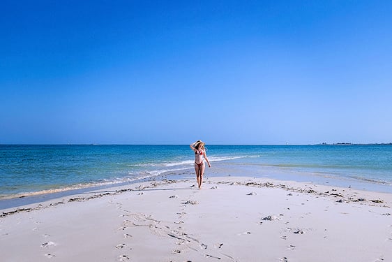 Woman walking along an exposed sandbar into shallow tidal water in northern Mozambique.