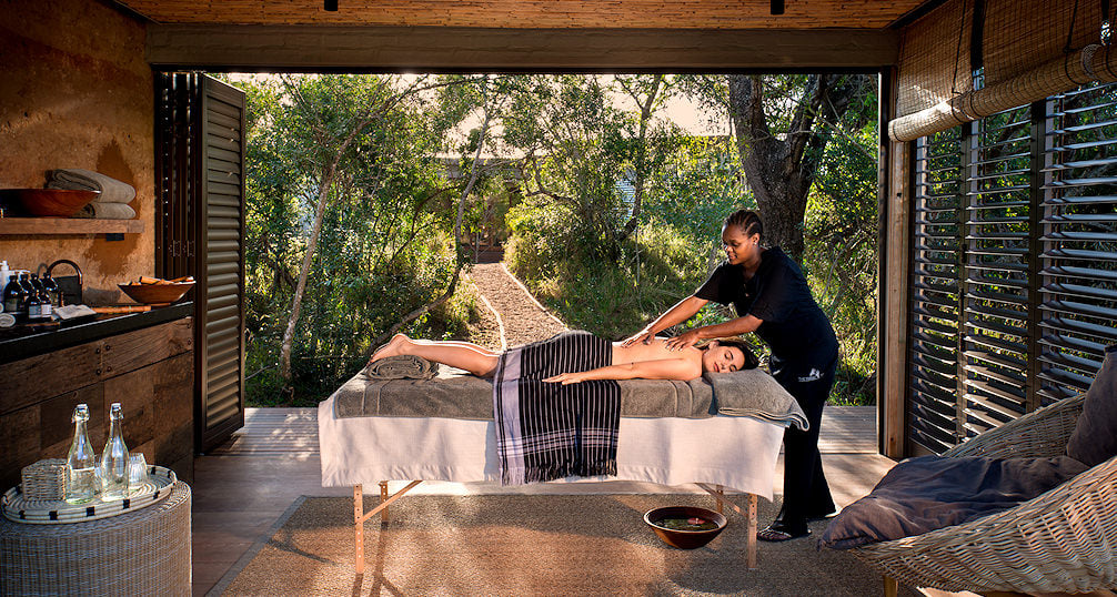 Therapist applying African botanical oils during a luxury African safari wellness experience.
