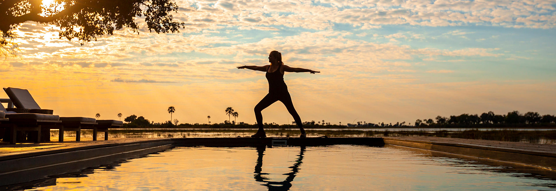 Guest practicing sunrise yoga at a luxury safari lodge overlooking the African savannah during a private African safari tour.