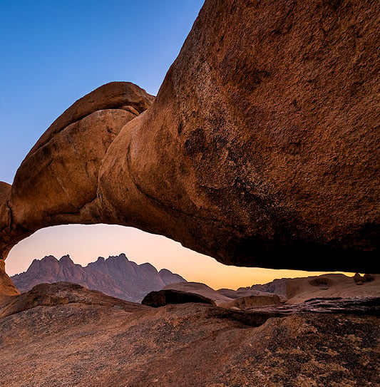 A large natural rock arch framing the distant mountains at Spitzkoppe in Damaraland.