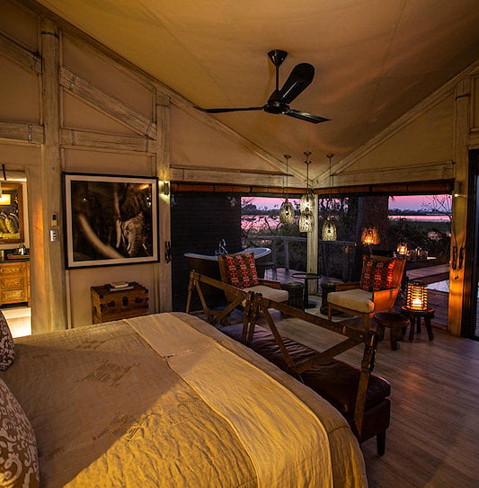 Bedroom opening onto a plunge pool and deck above Okavango Delta floodplains at dusk.