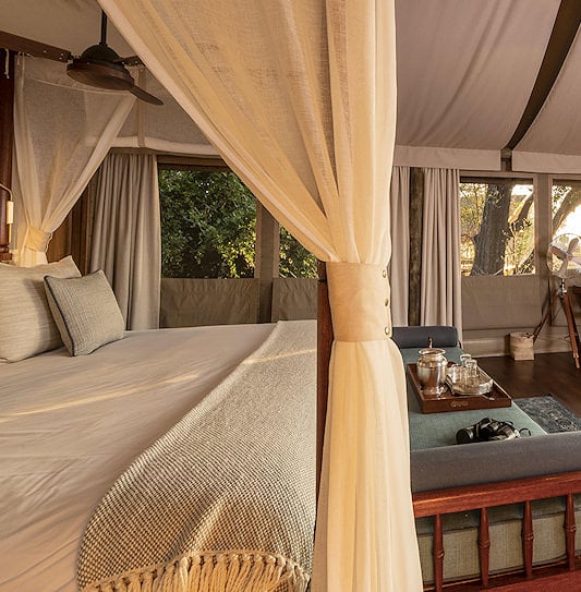 Canopy bed and writing desk in a canvas room with sliding doors to the bush, in the northern Okavango Delta.