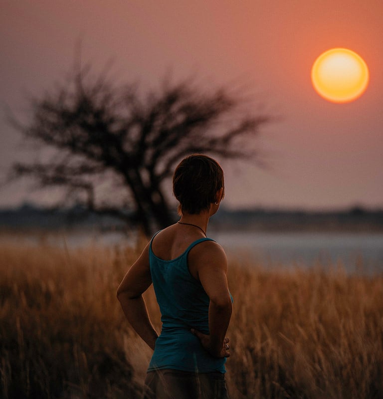 A traveler looking out over open floodplains as the sun sets.