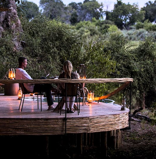 Guests at Wilderness Mombo Camp sitting on a private deck overlooking the Okavango Delta, Botswana.