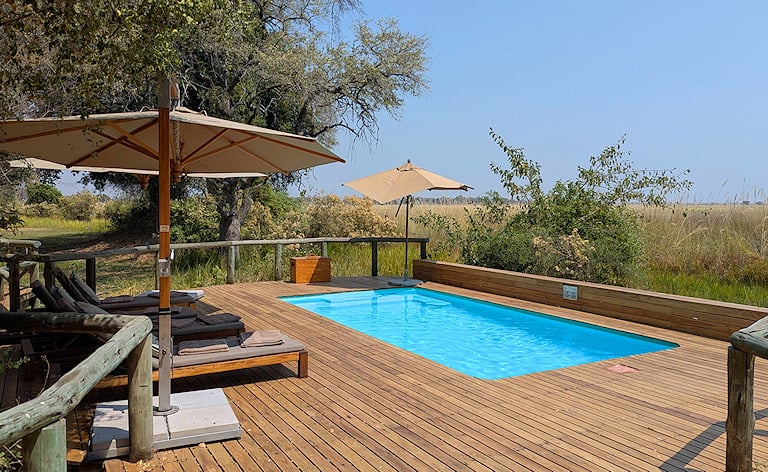 Wooden lodge deck with a swimming pool and sun loungers, Okavango Delta, Botswana.