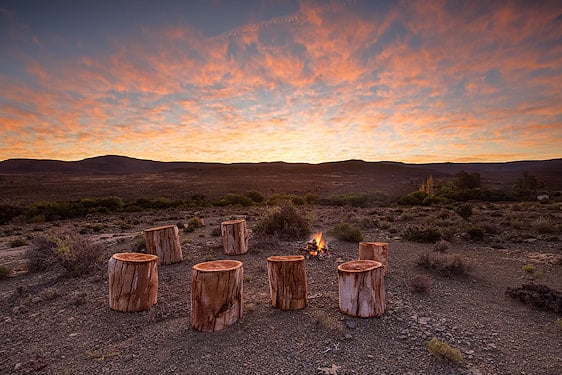 Wooden log seating around a campfire on a hillside in the Central Kalahari