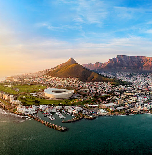 An aerial panoramic view of Cape Town, South Africa, featuring Table Mountain, the city bowl, and the harbor.