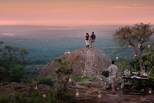 A couple standing on a rock overlooking the wilderness of Phinda.
