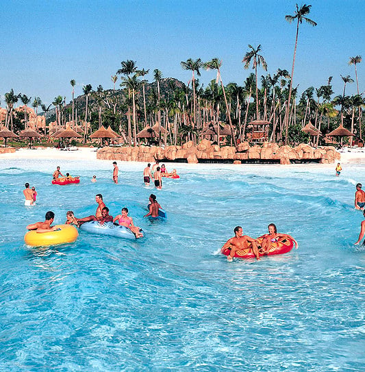 Families swimming in a man-made wave pool at Sun City resort in South Africa.
