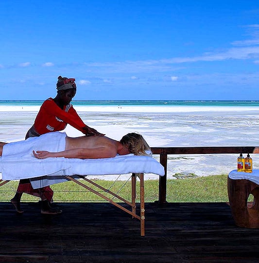 A guest at Coral Lodge in Mozambique enjoying a massage on an outdoor deck with a sea view.