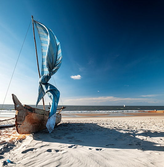 A traditional wooden sailing boat resting on a beach in Mozambique.