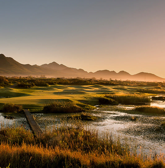 A scenic panoramic view of The Links golf course at Fancourt in South Africa, with mountains in the background.