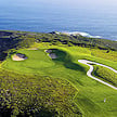 Overhead view of a coastal golf green cut into cliffs above the ocean.