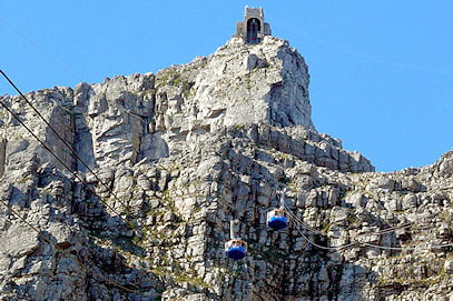 Two cable cars ascending the rocky cliff face of Table Mountain in Cape Town.
