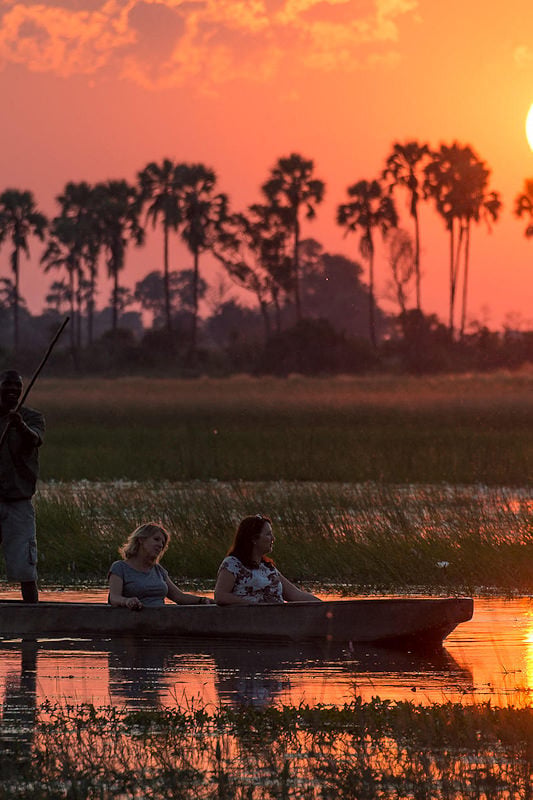 Guests experiencing a mokoro ride on the floodplains at sunset in the Okavango Delta.