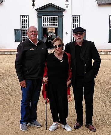 A senior couple and their tour guide posing outside a historic Cape Dutch building.