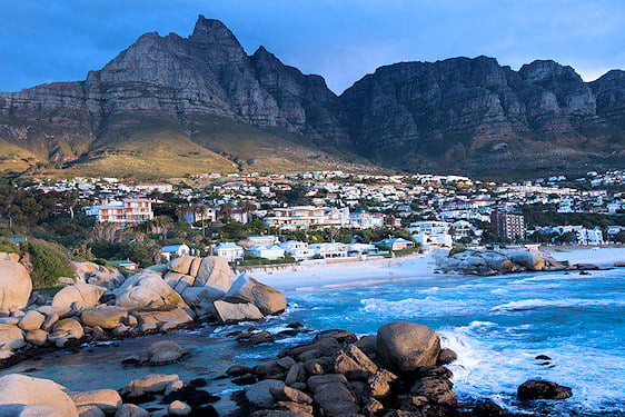Boulder-lined coastline and beach below the Twelve Apostles mountain range, Camps Bay, Cape Town.