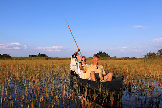 Travelers on a guided mokoro excursion through reed channels in the Okavango Delta, Botswana.