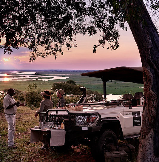 Visitors and a ranger enjoying sunset cocktails overlooking the river in Chobe National Park.