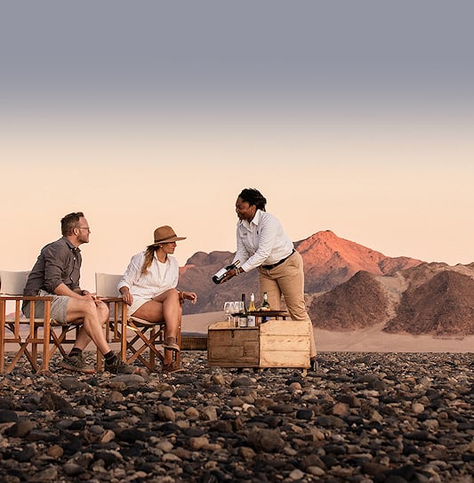 Guests enjoy a luxury wine tasting experience in the arid Kulala Wilderness Reserve near Sossusvlei, Namibia.