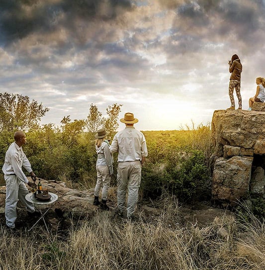 Guests enjoy sunset cocktails at a viewpoint in Madikwe Game Reserve, South Africa.