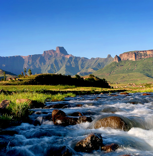 A rushing river with the Drakensberg mountains of KwaZulu-Natal, South Africa in the background.