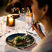 A guest enjoying a candlelit fine dining meal with wine at a safari lodge.
