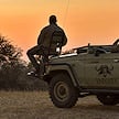A safari tracker sitting on the front hood seat of a 4x4 game drive vehicle at sunset.