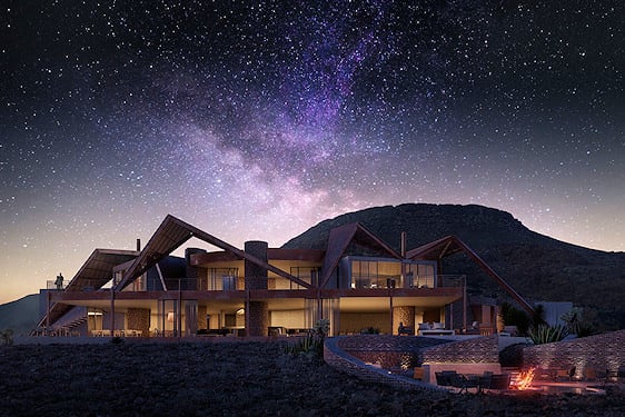 A modern desert safari lodge illuminated under a clear starry night sky.