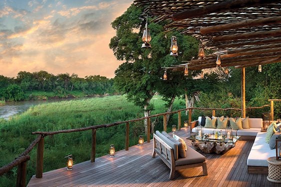 An elevated patio decorated with hanging oil lanterns overlooking a river channel in Kruger.