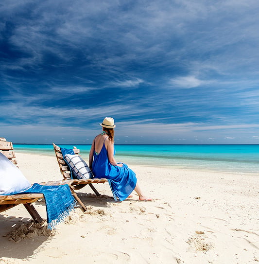 A woman enjoys a view of the turquoise ocean and white sand beach on vacation in Mozambique.
