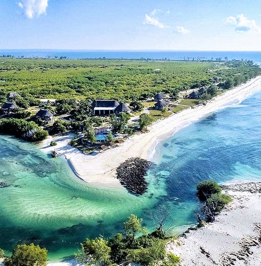 Aerial view of a sandy peninsula encircled by mangroves and coastal lagoon channels in Mozambique.