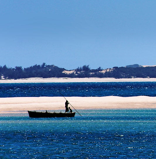 A fisherman on the blue ocean surrounded by the white sandy islands of the Bazaruto Archipelago, Mozambique.
