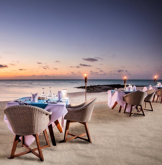 Dinner tables illuminated by torches on the beach at a luxury resort in the Quirimbas Archipelago, Mozambique.