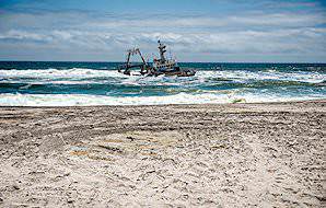 A shipwreck is beaten by the waves in the shallows along the Skeleton Coast.