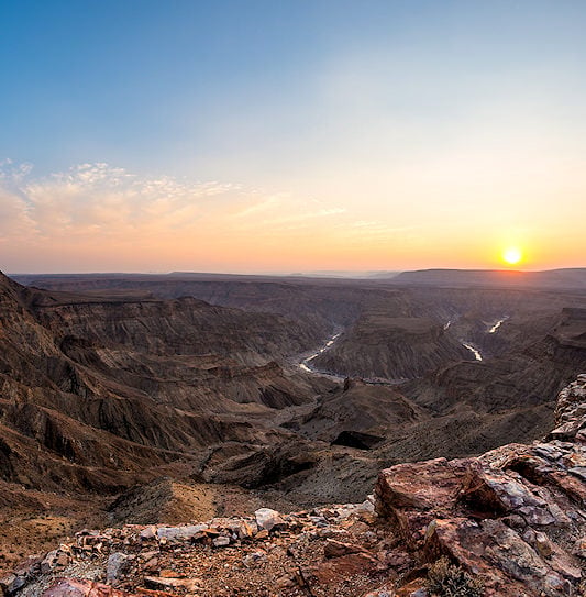 The sun setting over the deep, winding ravines of Fish River Canyon.