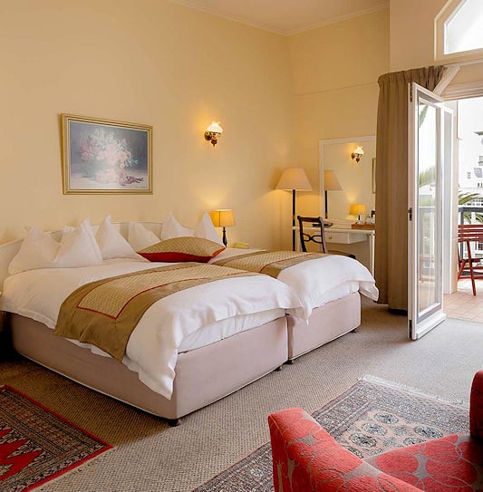 Bedroom with a balcony overlooking palms and colonial buildings in Swakopmund.