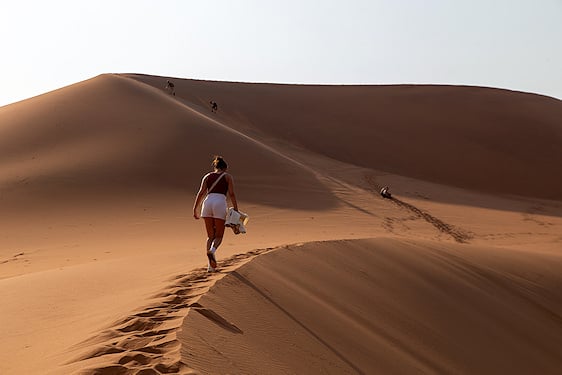 Woman hiking along the crest of a high desert sand dune.