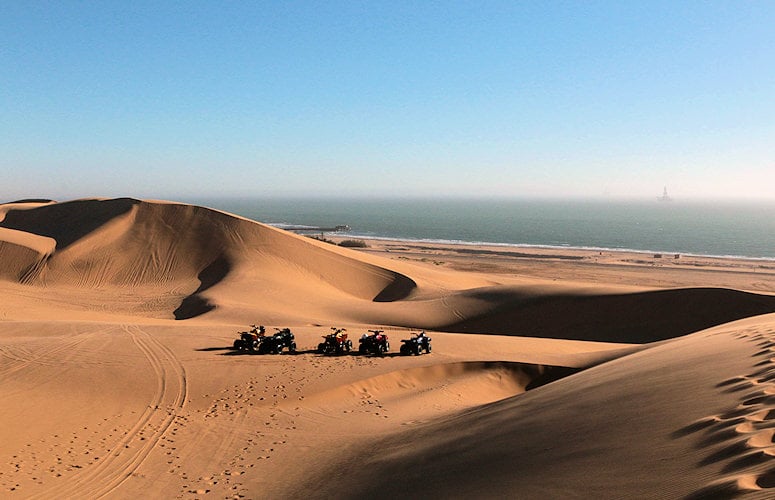 Quad bikes parked on sand dunes overlooking the coast near Swakopmund, Namibia.